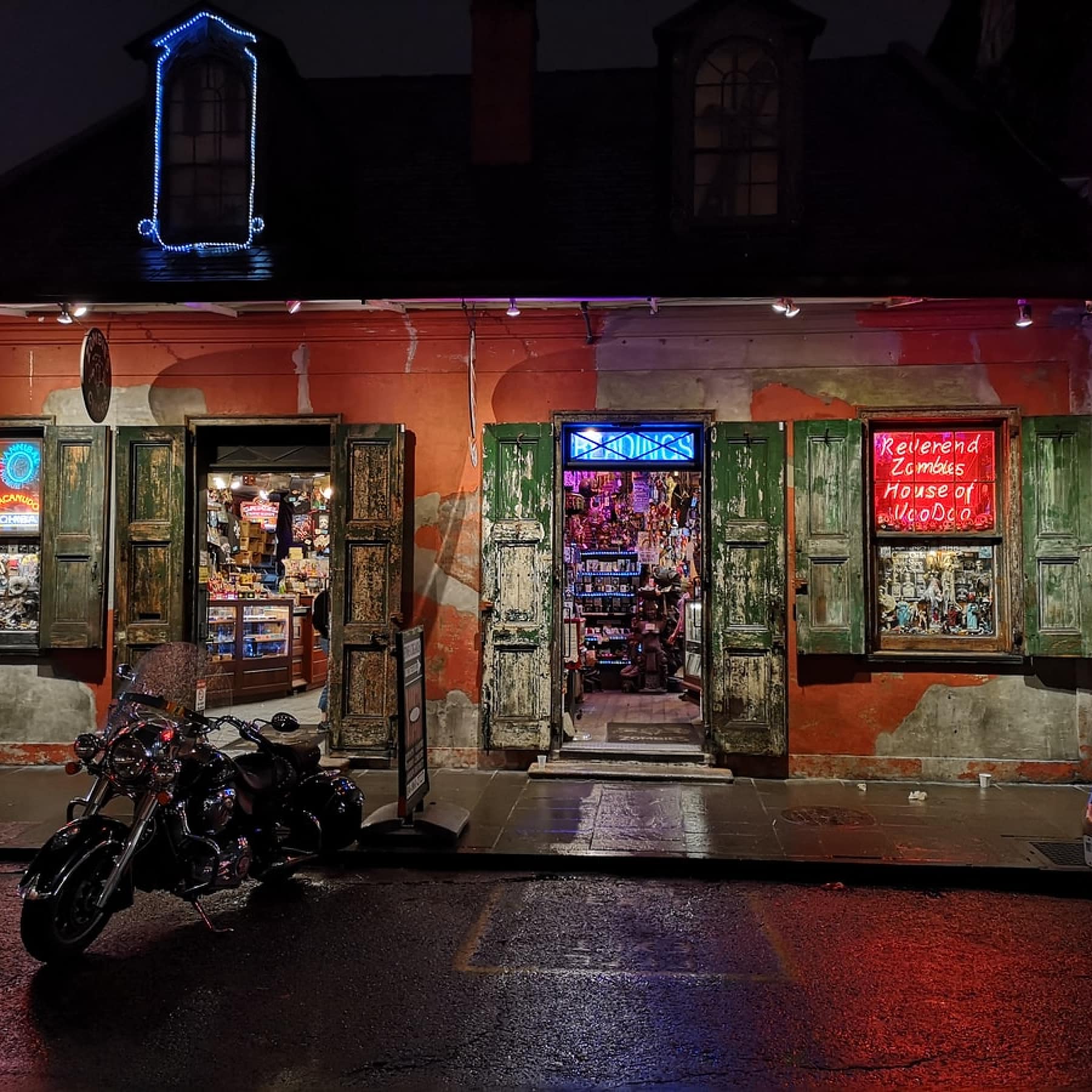A street in New Orleans with a store about Voodoo related things, neon lighting throughout